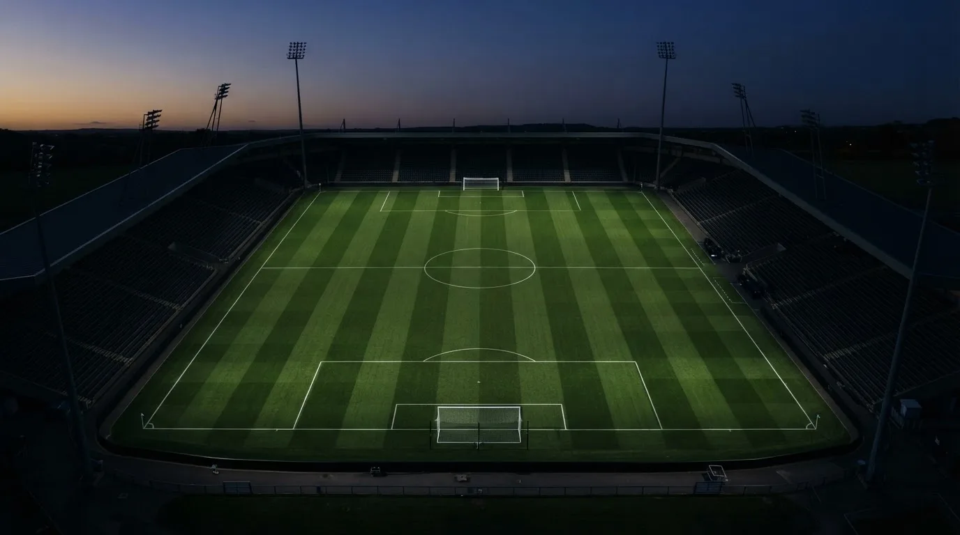 Ein Fußballplatz am Abend aus der Vogelperspektive, Flutlichtmasten ausgeschaltet, die Rasenlinien deutlich sichtbar.