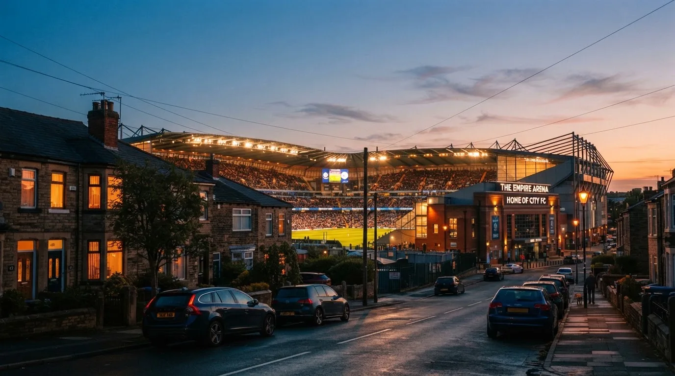 Ein Stadion aus der Ferne bei Flutlicht, davor eine ruhige Straße in der Abenddämmerung.